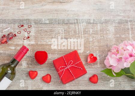 Rotwein-Flasche und Liebe Geschenk-Boxen, Kerzen, Blumen auf Holzhintergrund. Valentinstag. Das Konzept von Urlaub und Liebe. Flach liegend Stockfoto