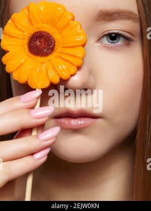 Teenager Mädchen mit Blume Lollipop in den Händen schließen Auge. Naschkatzen-Konzept. Stockfoto