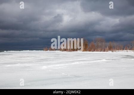 Ein Wintersturm nähert sich den Ufern der Southern Georgian Bay in Lighthouse Point, Collingwood. Eis erstreckt sich über die Bucht mit düsteren, bedrohlichen Wolke Stockfoto