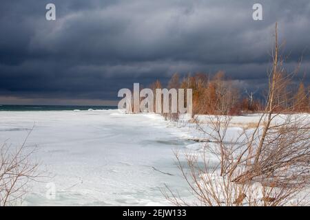 Ein Wintersturm nähert sich den Ufern der Southern Georgian Bay in Lighthouse Point, Collingwood. Eis erstreckt sich über die Bucht mit düsteren, bedrohlichen Wolke Stockfoto