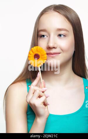 Lächelndes Teenager-Mädchen mit Blume Lollipop in den Händen. Naschkatzen-Konzept. Stockfoto