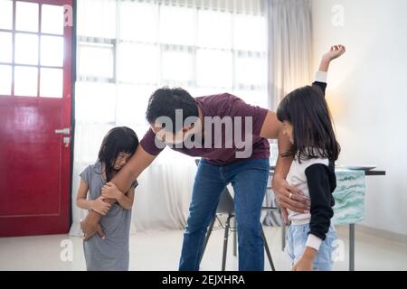 asiatische kleine Kinder, Schwester kämpfen um ein Spielzeug. Der Konflikt zwischen Kindern Vater versuchen, es zu stoppen Stockfoto