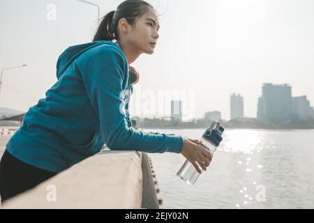 Frau Sportlerin durstig macht eine Pause. Sie hält Wasserflasche nach dem Laufen. Stockfoto