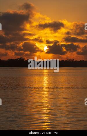 Atmosphärischer Blick auf einen roten Himmel mit Spiegelung der aufgehenden Sonne im Meer, Miara, Queensland, QLD, Australien Stockfoto