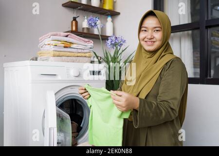 Frau in Hijab dabei Kleidung Wäsche zu Hause mit Waschen Maschine Stockfoto