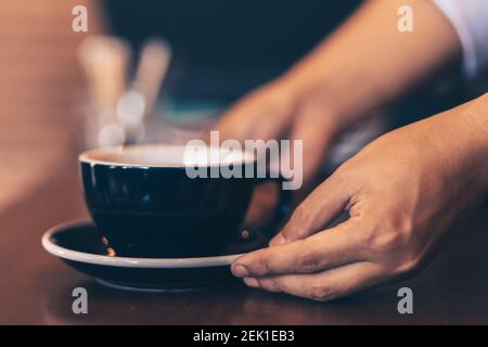 Barista serviert dem Gast im Café einen Kaffee. Stockfoto