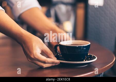 Barista serviert dem Gast im Café einen Kaffee. Stockfoto
