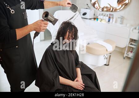 Salon professionell mit einer Paddelbürste und einem Fön Stockfoto