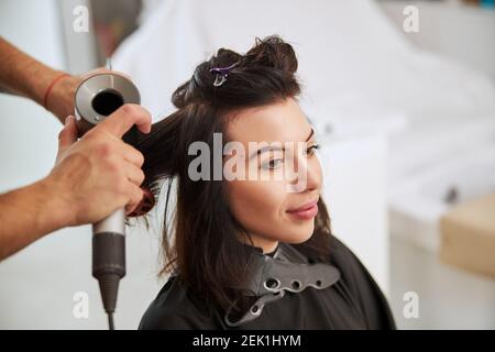 Professionelle Stylistin Locken weibliche Haare mit einem Fön Stockfoto