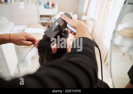 Professionelle Stylistin mit Friseur-Tools für die Herstellung Locken Stockfoto