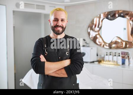 Fröhliche attraktive Friseur posiert für die Kamera Stockfoto