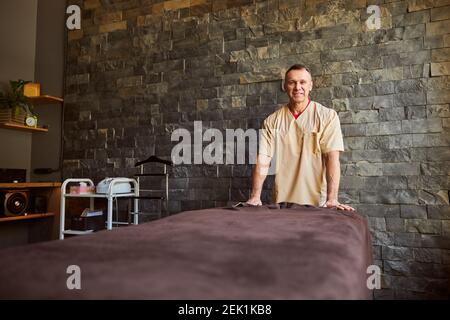 Freundlicher männlicher Spa-Therapeut, der an seinem Arbeitsplatz posiert Stockfoto