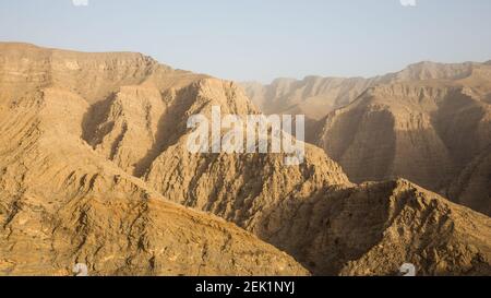 Felsige und karge Hajar Mountains Bergkette während des Sonnenuntergangs vom Jebel Jais Aussichtsplattform Park, Vereinigte Arabische Emirate. Stockfoto