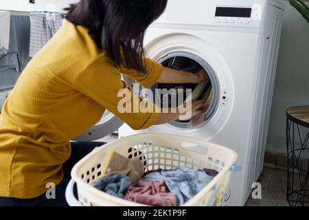 Nahaufnahme einer Frau vor der Waschmaschine Wäsche waschen und Wäsche darin einlegen Stockfoto