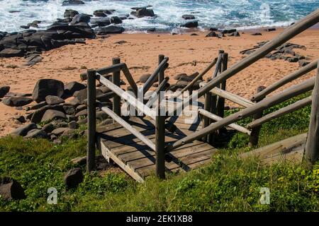 Holztreppe, die zum felsigen Strand führt Stockfoto