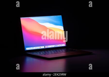 Das neue MacBook Air mit Apples M1 Chip und dem neuesten macOS Big Sur isoliert auf einem Schreibtisch im Dunkeln. Stockfoto