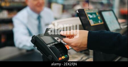 Nahaufnahme einer nicht erkennbaren Person, die im Supermarkt mit Kreditkarte bezahlt. Der Kunde, der den Kauf mit seiner nfc-Karte bei Superm bezahlt Stockfoto