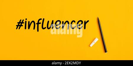 Handgeschriebenes Influencer-Wort mit Hashtag-Symbol und einem Stift-Marker auf gelbem Hintergrund. Social Media Influencer Konzept. Stockfoto