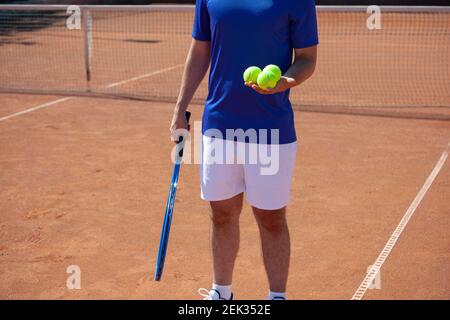 Tennisspieler mit Tennisschläger und drei Bällen Ein Tennisspielplatz Stockfoto
