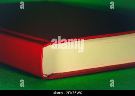 Nahaufnahme eines alten roten Buches auf grünem Hintergrund. Selektive geringe Schärfentiefe. Stockfoto