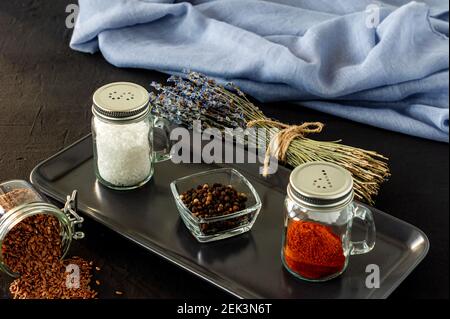 Pfeffer- und Salzglas-Shaker auf schwarzem Beton-Backgroun mit Kopierraum. Stockfoto