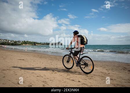 Radfahren am Strand von Milford mit unfokussieren Leuten, die ihren morgendlichen Spaziergang machen. Stockfoto