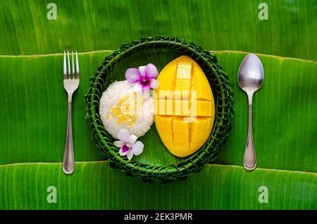 Thai Dessert - Mango klebrigen Reis auf Bananenblatt Teller mit Gabel und Löffel auf Bananenblatt Hintergrund gesetzt. Stockfoto