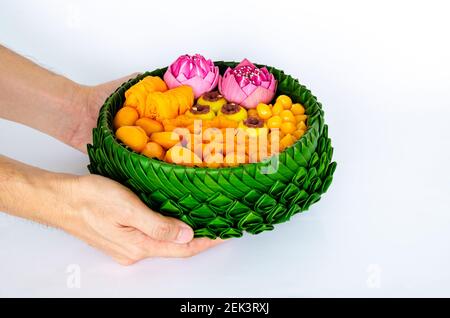 Hand hält teilweise Fokus der thailändischen Hochzeit Desserts auf Bananenblätter Teller oder krathong für thai traditionelle Zeremonie auf weißem Hintergrund. Stockfoto