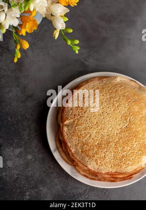 Traditionelle hausgemachte dünne Pfannkuchen, Blini mit Frühlingsblumen Stockfoto