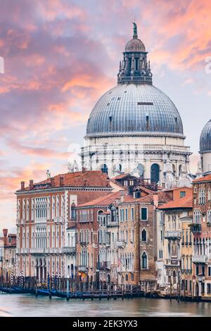 Atemberaubende Aussicht auf die Skyline von Venedig mit dem Canal Grande und der Basilika Santa Maria della Salute in der Ferne bei einem dramatischen Sonnenaufgang. Stockfoto