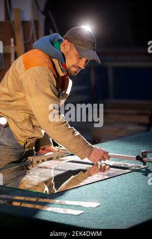 Ein Arbeiter schneidet einen Spiegel mit einem Glasschneider. Stockfoto