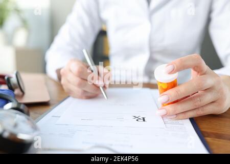 Arzt schreibt Rezept und hält Glas Pillen in Seine Hände Stockfoto