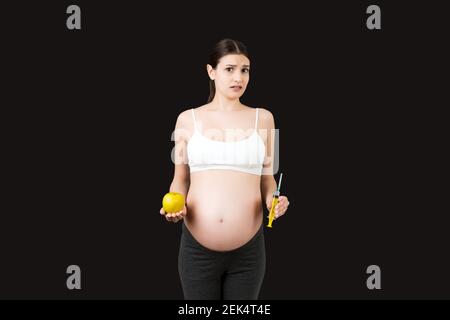 Spritze zur Injektion in die Hand der schwangeren Frau auf farbigem Hintergrund mit Kopierraum. Medizinische Behandlung während der Schwangerschaft Konzept. Stockfoto
