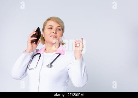 Vocal Messaging bei der Arbeit. Porträt eines leitenden Apothekers, der in der Apotheke auf dem Mobiltelefon spricht. Frau, die mit dem Zeigefinger auf den leeren Bereich zeigt Stockfoto