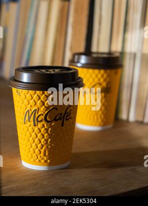 Ukraine, Kiew - 17. Februar 2021: Gelbes Glas Kaffee von McDonald's. Papierglas Drink McCafe. Kaffeetasse auf Tisch mit Schatten. Menü in Fastfood Stockfoto