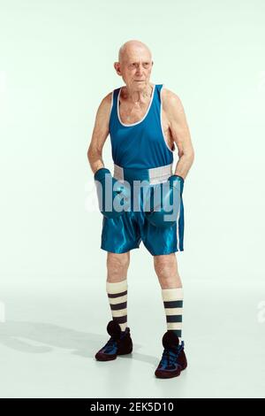 Senior Mann trägt Sportbekleidung Boxen isoliert auf Studio Hintergrund. Kaukasisches männliches Modell in guter Form bleibt aktiv und sportlich. Konzept von Sport, Aktivität, Bewegung, Wohlbefinden. Copyspace, Anzeige. Stockfoto