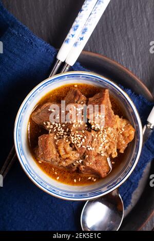 Essen Konzept Spot Fokus hausgemachte koreanische Rindfleisch Eintopf in orientalischen Stil Porzellanbecher auf schwarzem Hintergrund mit Kopierraum Stockfoto