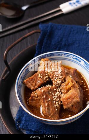 Essen Konzept Spot Fokus hausgemachte koreanische Rindfleisch Eintopf in orientalischen Stil Porzellanbecher auf schwarzem Hintergrund mit Kopierraum Stockfoto