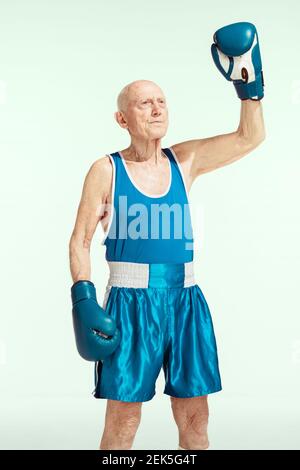 Champion. Senior Mann trägt Sportbekleidung Boxen auf Studio Hintergrund. Kaukasisches männliches Modell in guter Form bleibt aktiv und sportlich. Konzept von Sport, Aktivität, Bewegung, Wohlbefinden. Copyspace, Anzeige. Stockfoto