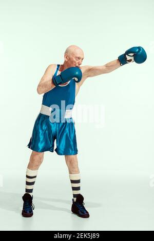 Champion. Senior Mann trägt Sportbekleidung Boxen auf Studio Hintergrund. Kaukasisches männliches Modell in guter Form bleibt aktiv und sportlich. Konzept von Sport, Aktivität, Bewegung, Wohlbefinden. Copyspace, Anzeige. Stockfoto