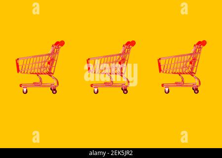 Warenkorb in einem Supermarkt. Leeren Sie den roten Warenkorb in einem Geschäft auf gelbem Hintergrund. Minimalistischer Stil. Verkauf, Rabatte, Shopaholism Konzept. Stockfoto