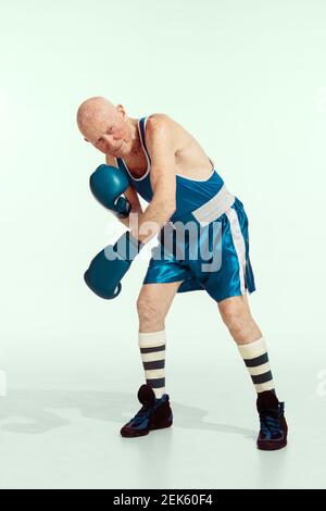 Coach. Senior Mann trägt Sportbekleidung Boxen auf Studio Hintergrund. Kaukasisches männliches Modell in guter Form bleibt aktiv und sportlich. Konzept von Sport, Aktivität, Bewegung, Wohlbefinden. Copyspace, Anzeige. Stockfoto