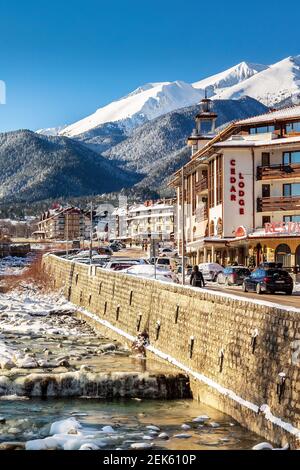 Bansko, Bulgarien - 28. Januar 2021: Fluss Glazne in der bulgarischen Stadt, Hotelhäuser und Schnee Pirin Berge Stockfoto