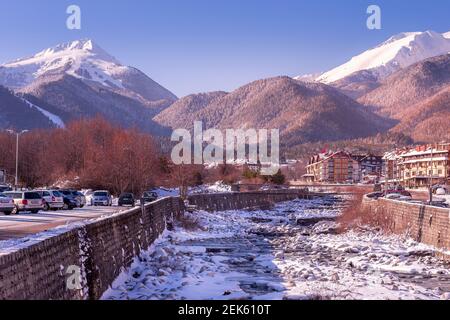 Bansko, Bulgarien - 28. Januar 2021: Fluss Glazne in der bulgarischen Stadt, Hotelhäuser und Schnee Pirin Berge Stockfoto