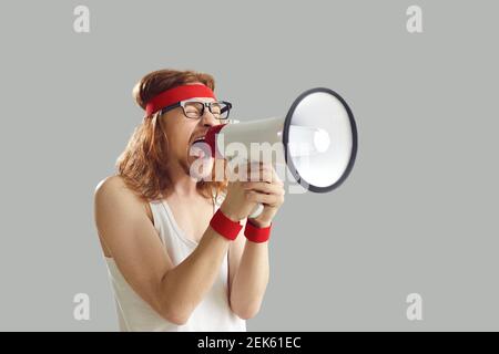 Lustige junge Mann in Retro-Sportbekleidung schreien in Megaphon isoliert Auf grauem Hintergrund Stockfoto
