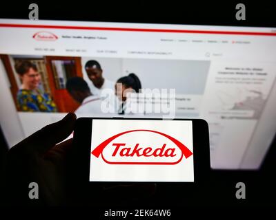 Person, die Smartphone mit Logo der japanischen Takeda Pharmaceutical Company Limited auf dem Bildschirm vor der Website hält. Konzentrieren Sie sich auf die Telefonanzeige. Stockfoto