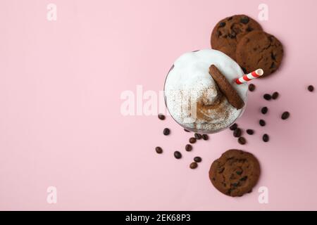 Glas Milchshake, Kaffeesamen und Kekse auf rosa Hintergrund Stockfoto