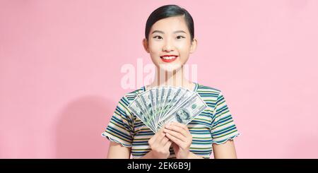 Aufgeregt junge Frau Mädchen posiert isoliert auf rosa Hintergrund Studio Porträt. Halten Sie Fan von Bargeld in Dollar-Banknoten Stockfoto