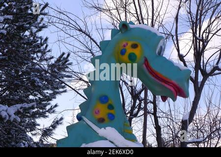 Dinosaurier Spielzeug auf dem Kinderspielplatz unter Schnee Stockfoto