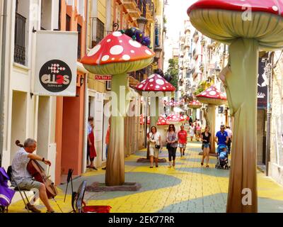 Alicante, Spanien - 18. Juli 2014: Straßenmusiker auf einer mit Pilzen geschmückten Straße. Stockfoto